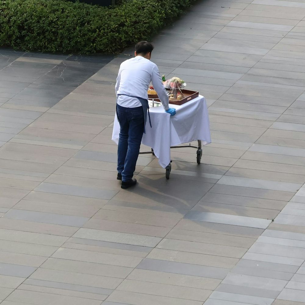 Camarero empujando un carro de servicio por la explanada de un hotel